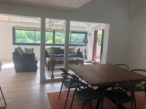 Una sala moderna con una mesa de comedor de madera, sillas negras y un sofá con cojines estampados.