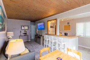 A modern living room with a sofa, a table, and a TV. - Cozy Ocean Beach Cottage Separate Entry and Clean (San Diego)