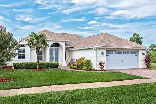 A single-story house with a garage, a covered patio, and a well-maintained lawn.