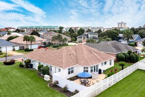 A residential area with houses, a fenced yard, and a patio with outdoor furniture.