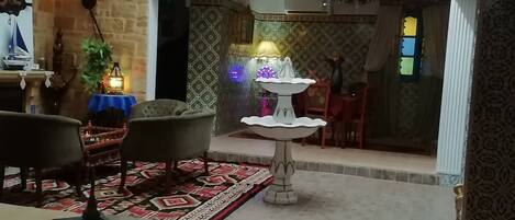 A spacious room with a high arched ceiling, a fountain centerpiece, and a patterned rug.