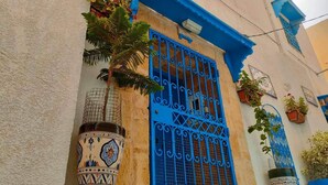 A building with a blue door and window, decorated with traditional tiles and potted plants. - Très jolie Riad, style Andalous au centre ville de Bizerte à 10 min de la plage! (Bizerte)