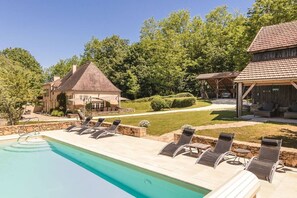 A swimming pool with lounge chairs and a covered patio area.