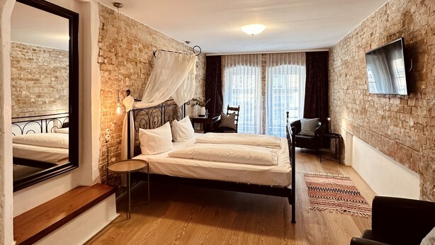 A bedroom with a bed, a TV, a chair, and a mirror. - cinderella.kreuzberg (Berlin)