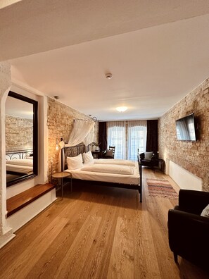 A bedroom with a bed, a TV, a chair, and a mirror. - cinderella.kreuzberg (Berlin)