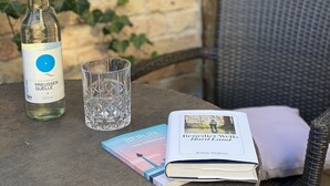 A bottle of Preussen Quelle still water, a glass, and a book on a round table outdoors. - cinderella.kreuzberg (Berlin)