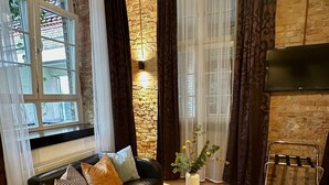 A modern living room with a black leather sofa, a round coffee table, and a stone wall. - cinderella.kreuzberg (Berlin)
