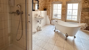 A bathroom with a glass-enclosed shower, a freestanding bathtub, and a sink with a mirror above it. - cinderella.kreuzberg (Berlin)