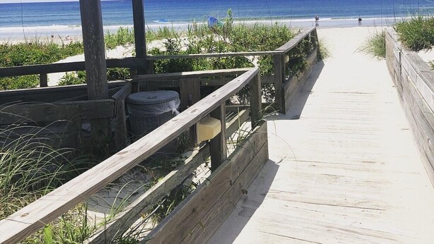 A wooden boardwalk leading to a beach with a wooden structure on the left. - Ocean-side condominium with pool and private beach access (Atlantic Beach)