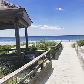 A wooden boardwalk leading to a beach with a wooden structure on the left. - Ocean-side condominium with pool and private beach access (Atlantic Beach)