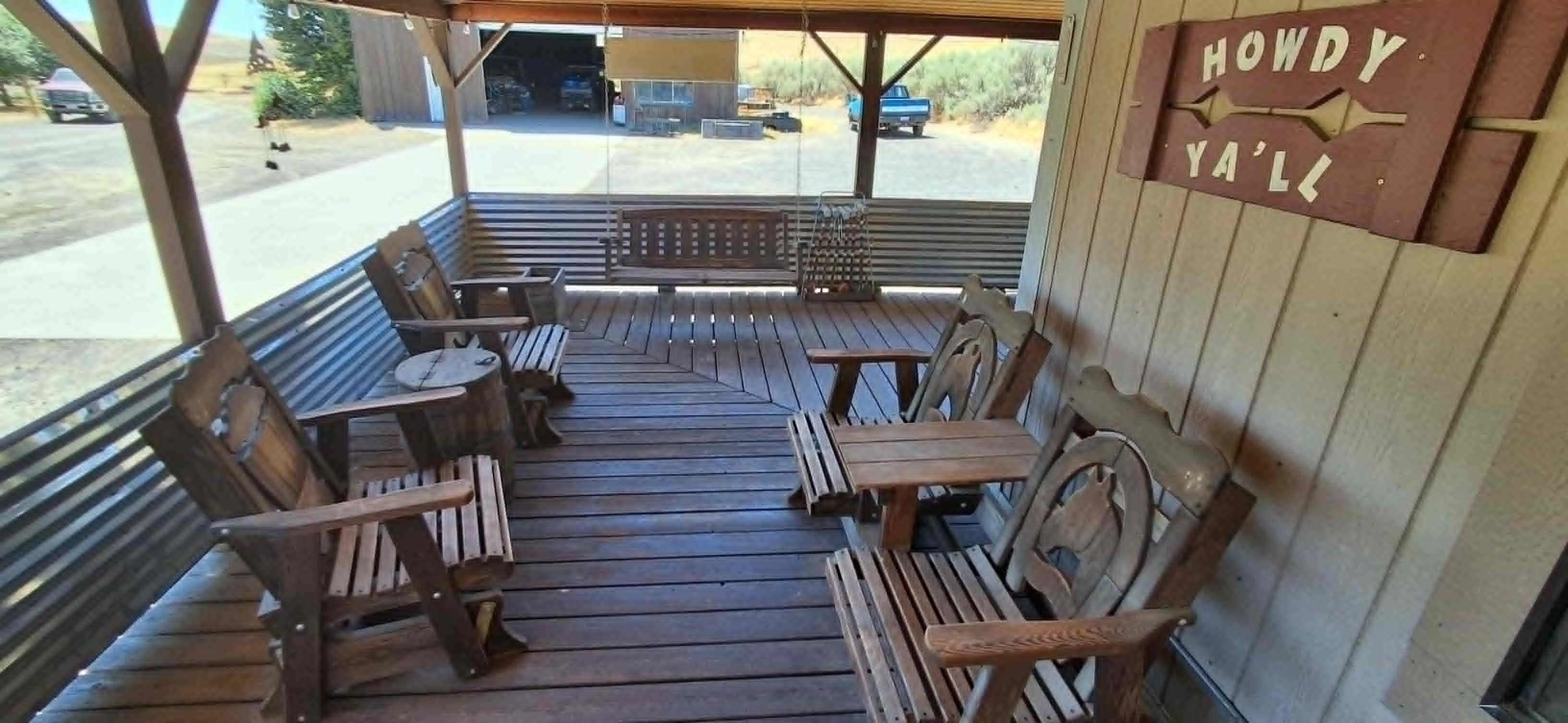 An outdoor wooden deck with seating and a sign reading 'HOWDY YALL'.