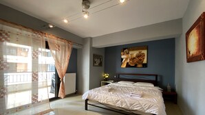 A bedroom with a bed, a nightstand, a wall-mounted painting, and a window with curtains.