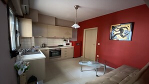 A modern kitchen with a dining area, a sofa, and a red accent wall.