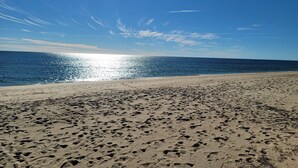 Een strand met voetafdrukken in het zand en een helderblauwe lucht.