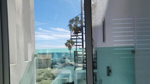 Uitzicht vanaf een balkon, met heldere lucht, een palmboom en een gebouw met een groene deur.