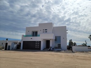 A modern two-story house with a garage, a balcony, and a clear view of the sky.