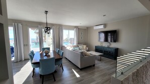 Een moderne woonkamer met een bank, eettafel en televisie.