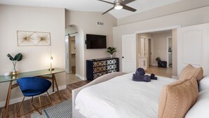 A spacious bedroom with a large bed, a desk with a chair, a ceiling fan, and a television. - On HGTV Show House Hunters! Heated Pool! Family & Dog friendly, Prime location!  (Gilbert)
