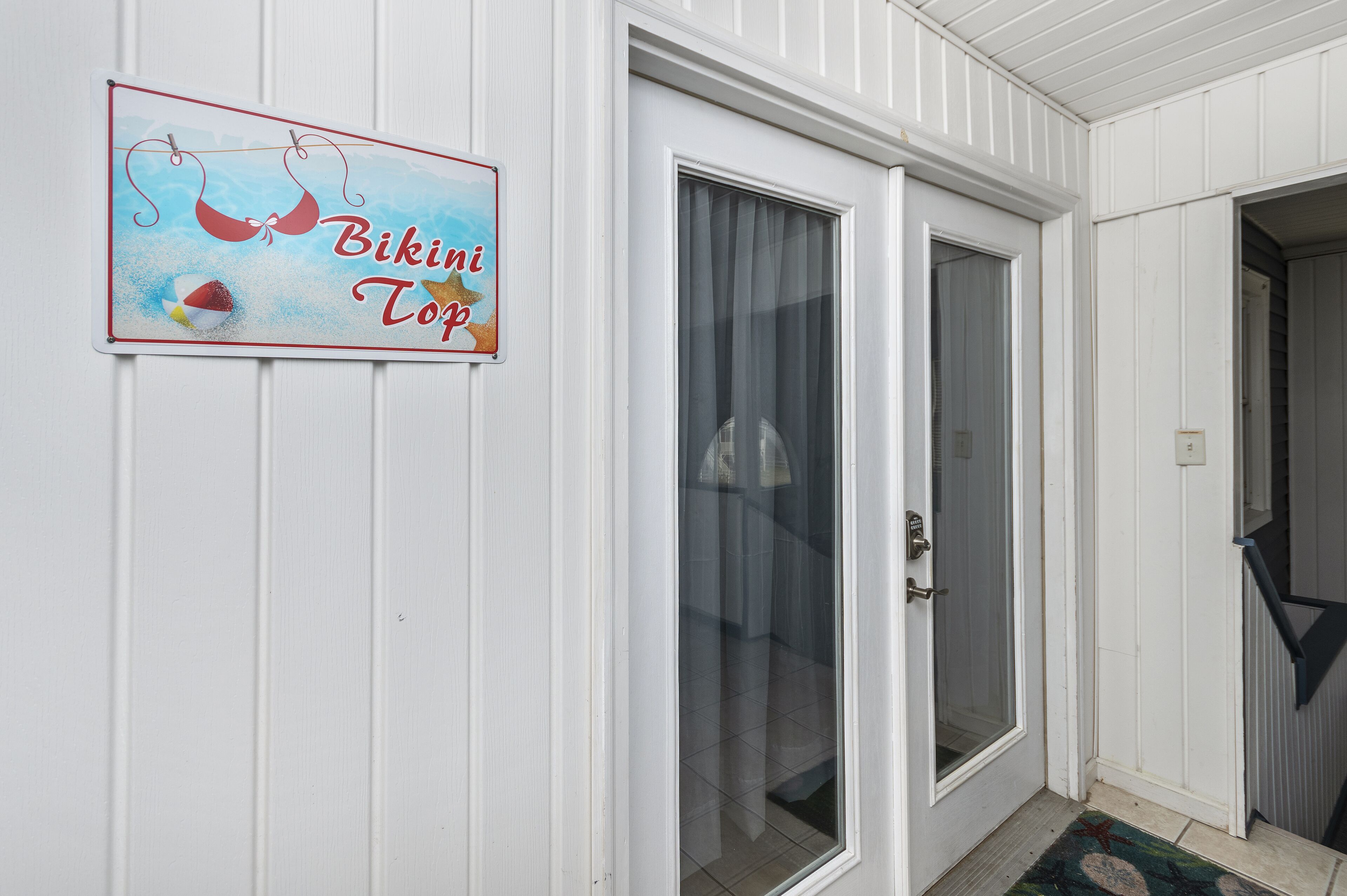 A door with a glass panel and a sign above it that reads "Bikini Top."