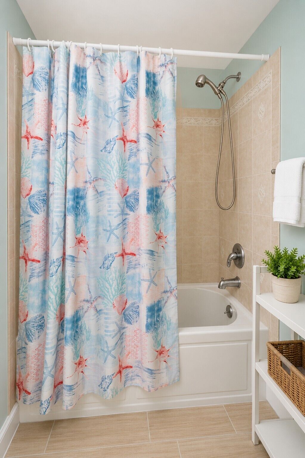 A bathroom with a shower curtain featuring a tropical pattern, a white bathtub, a handheld showerhead, and a shelf with a potted plant.