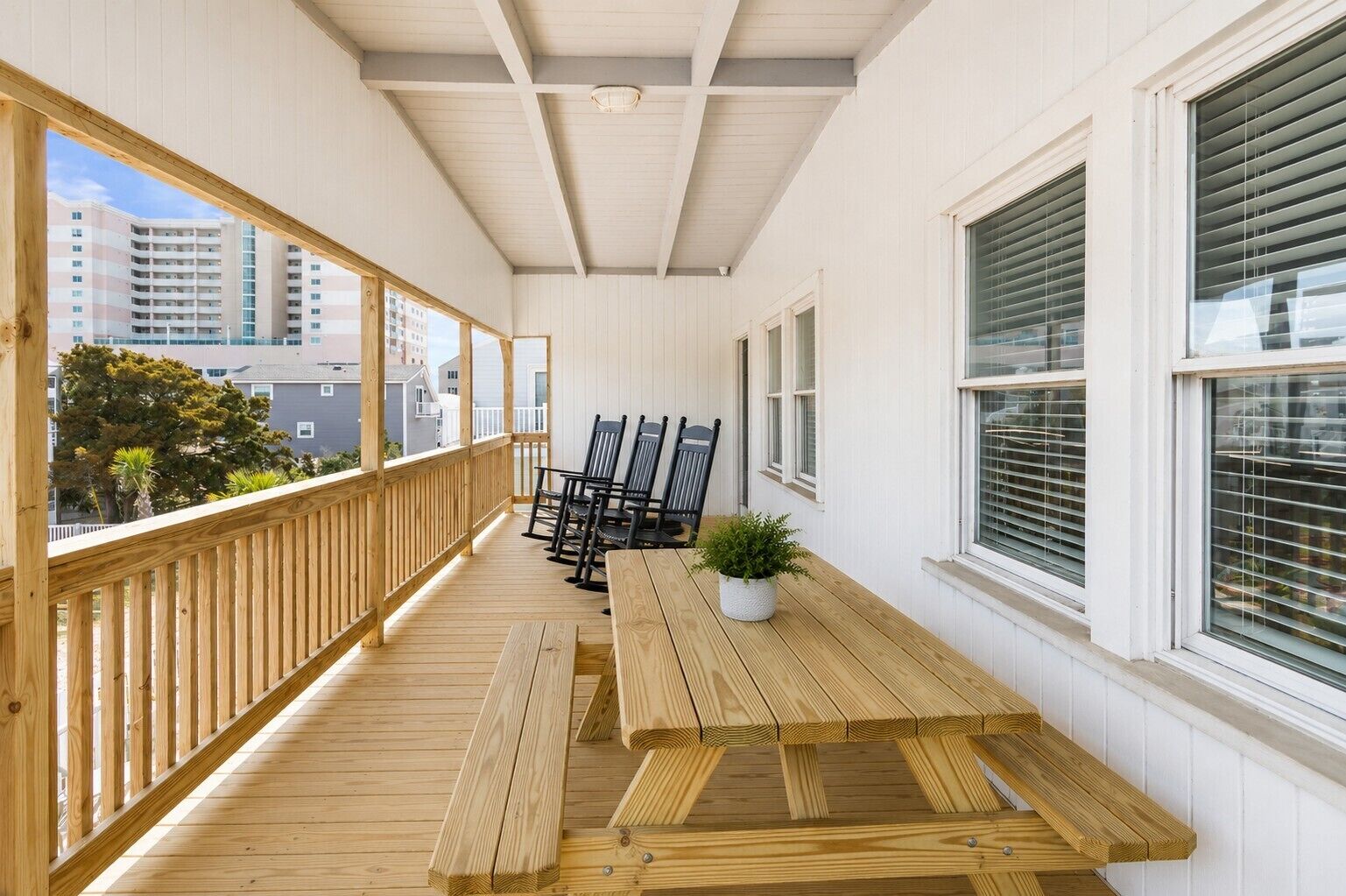 Une terrasse extérieure couverte, avec des bancs en bois, une table et des chaises.