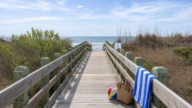 A wooden boardwalk leading to the beach with a beach ball and towel on the side. - 8BR/6Ba House, Private Pool, Minute Walk To Beach, Dog Friendly, Sleeps 24 (North Myrtle Beach)