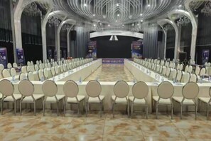 Un salón de conferencias con una larga mesa, varias sillas y pancartas.