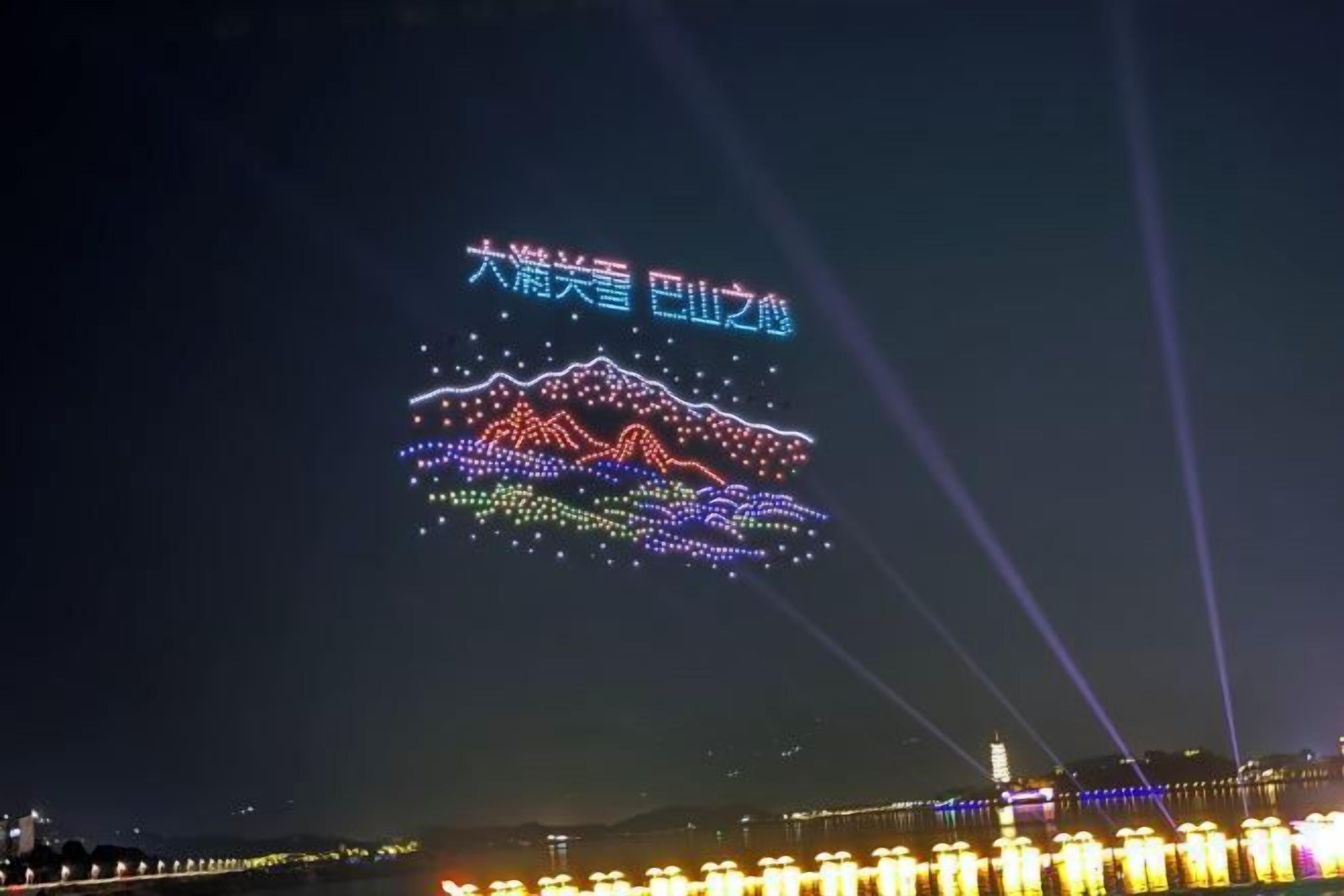 Vista nocturna de un paisaje urbano con texto iluminado y patrones de luz en el cielo.