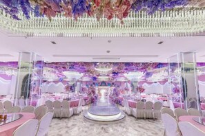 Een feestzaal met ronde tafels, stoelen en een centraal podium.