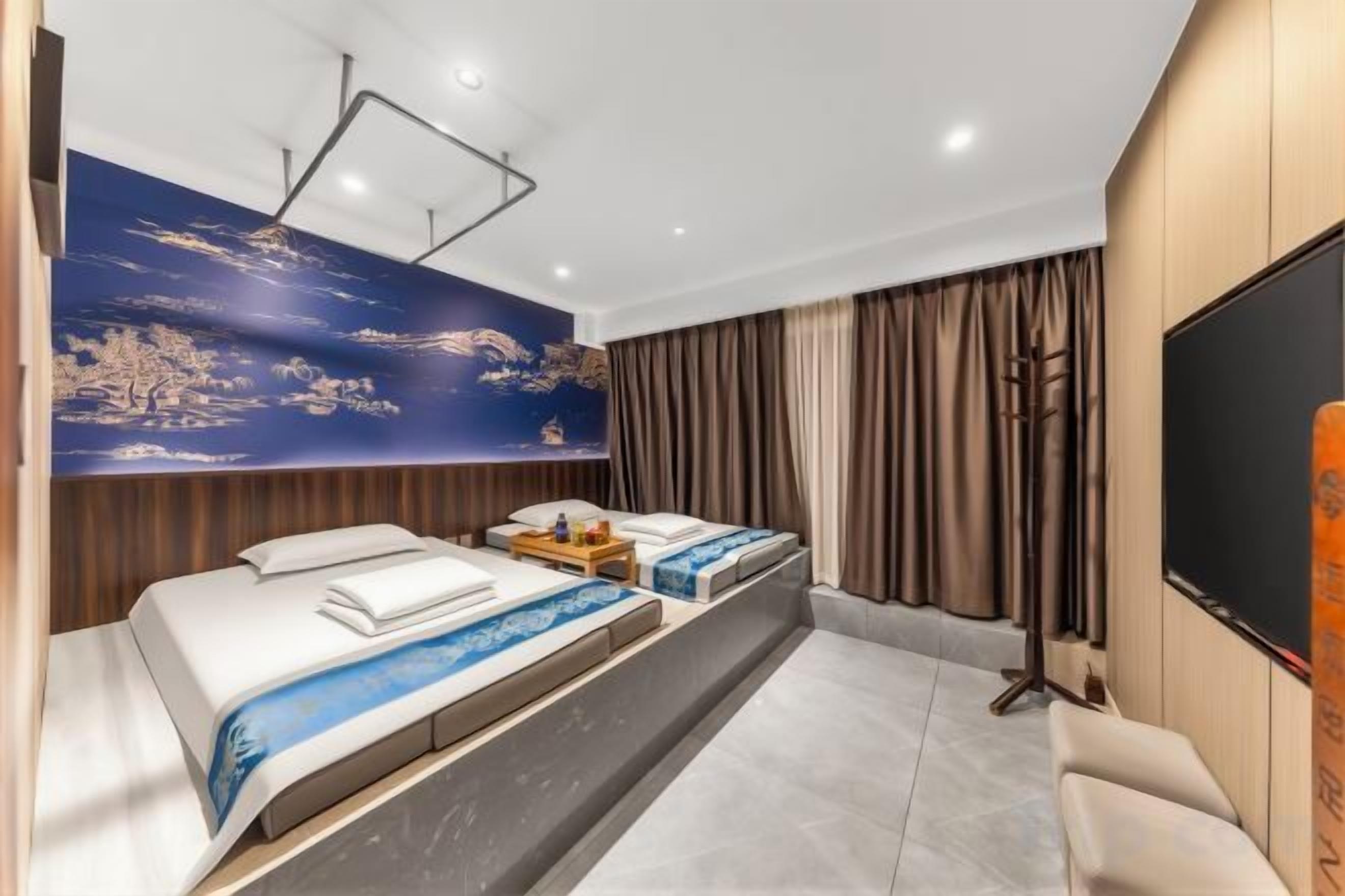 A hotel room with a large bed, a desk, a chair, a TV, and a wall with a painting.
