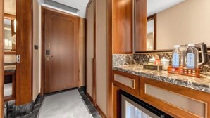 Un baño de hotel con puerta de madera, encimera de mármol y espejo.