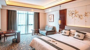 Una habitación de hotel con una cama grande, un sofá, un escritorio y una silla.