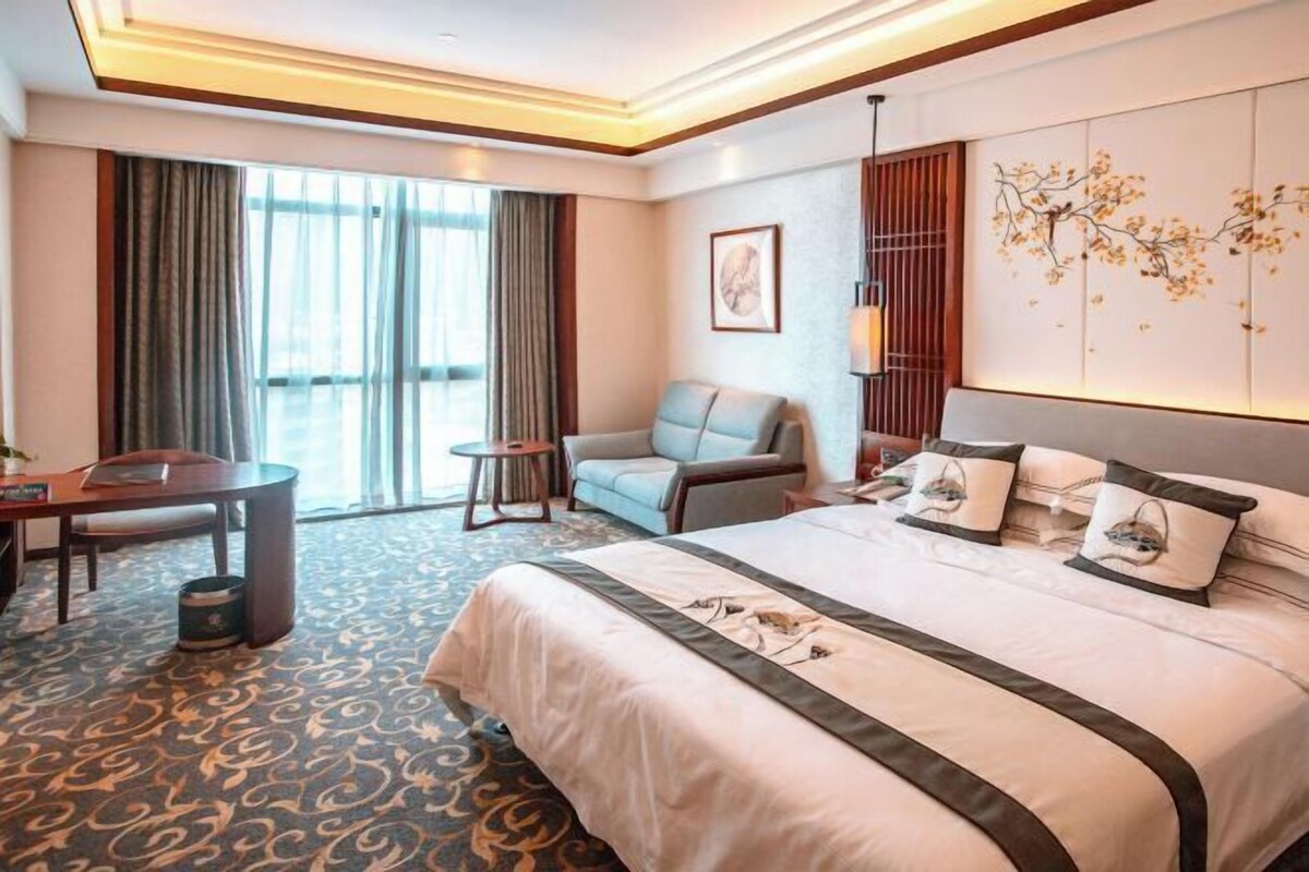 Una habitación de hotel con una cama grande, un sofá, un escritorio y una silla.