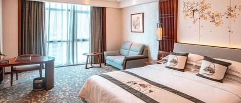 A hotel room with a large bed, a sofa, a desk, and a chair.