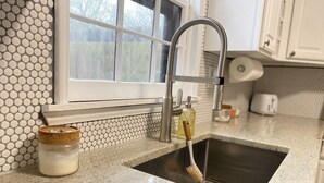 Une cuisine dotée d’un évier en acier inoxydable, d’une fenêtre offrant une belle vue et d’un dosseret décoré d’un motif en nid d’abeille.