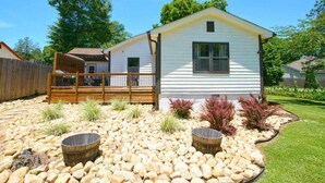 Une maison de plain-pied dotée d’une terrasse en bois, entourée d’un jardin aménagé avec des rochers et des arbustes.