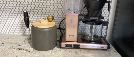 Eine Küche mit einer Kaffeemaschine, einer Waage und einem Behälter auf einer Arbeitsplatte.