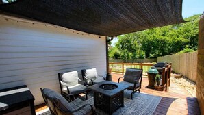 Un patio couvert aménagé avec du mobilier d’extérieur, notamment un canapé et des fauteuils, une table et un barbecue.