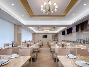 Uma sala de jantar de hotel com várias mesas, cadeiras e um candelabro.