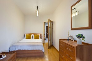 Un dormitorio con una cama de madera, un aparador, un espejo y una lámpara colgante.