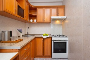 Una cocina con gabinetes de madera, un lavamanos de acero inoxidable, una estufa a gas y un horno empotrado.