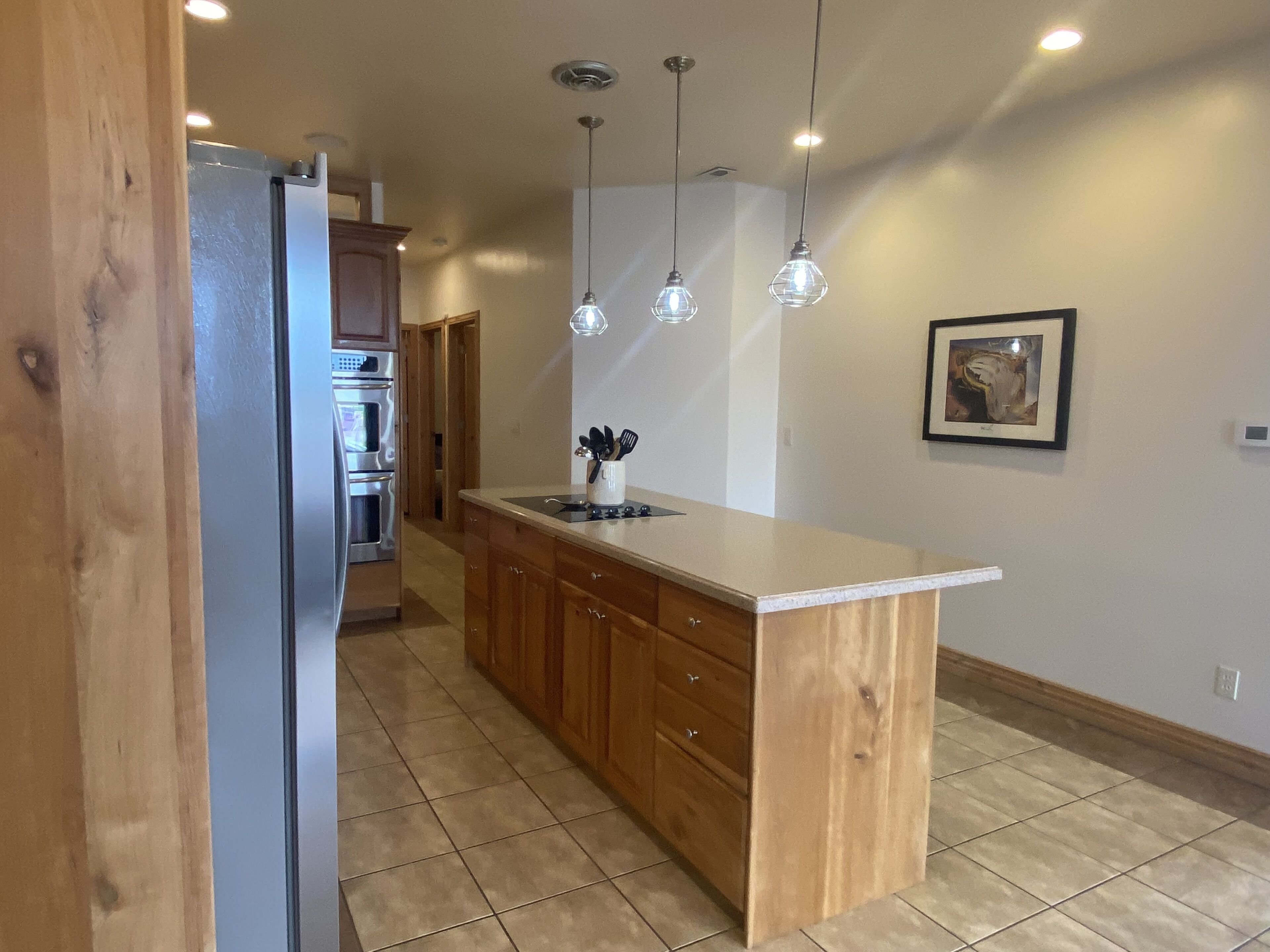 A kitchen with wooden cabinets, a central island, and pendant lighting.