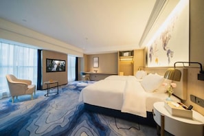 Une chambre d’hôtel avec un grand lit, un bureau, une chaise et une vue sur la ville.