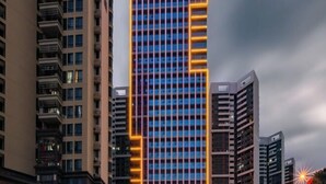 A high-rise building with a grid of windows and a prominent yellow-lit corner. - Kyriad Hotel (Zijin Wanhui Branch) (Zijin)