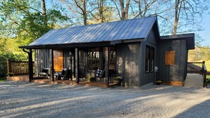 Une cabane rustique avec un toit en métal, une terrasse en bois et un porche équipé de sièges.