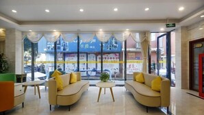 A hotel lobby with two sofas, a small round table, and large windows. - City Express Hotel (Longzhou)
