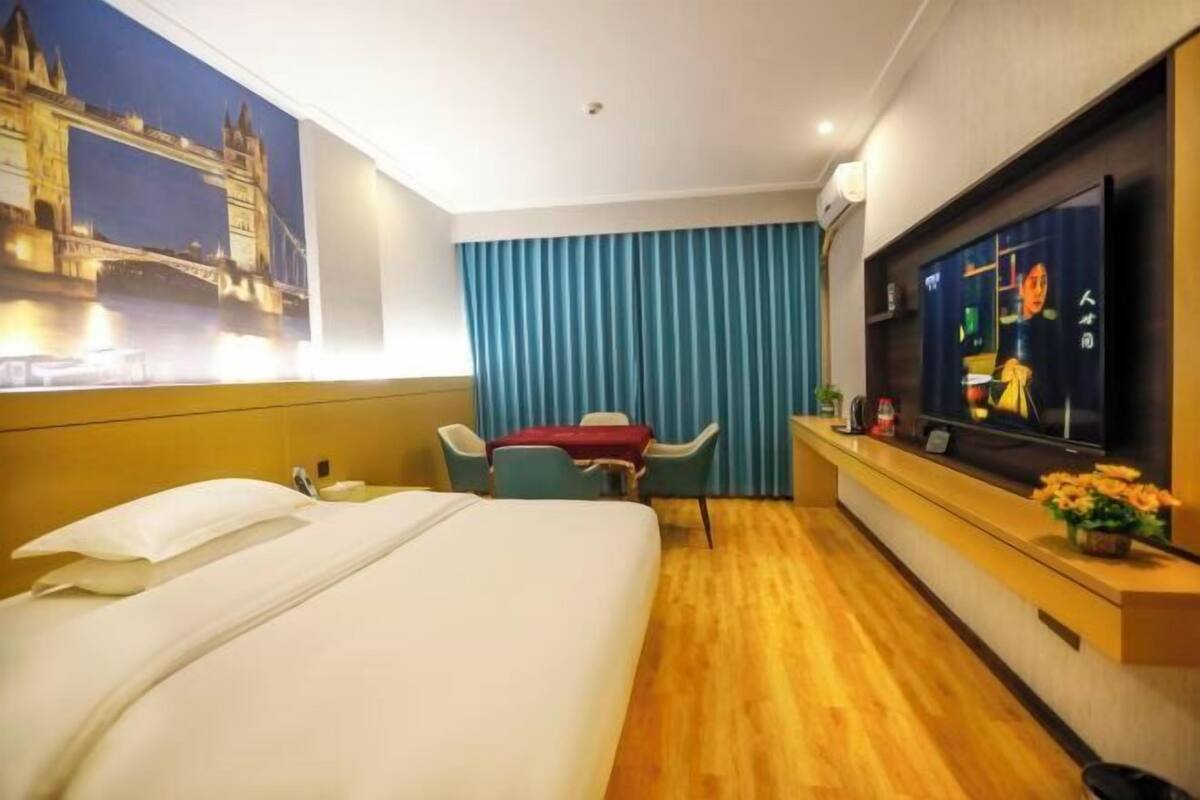 Habitación de hotel con cama, escritorio, silla, televisión y ventana con vista a un puente.