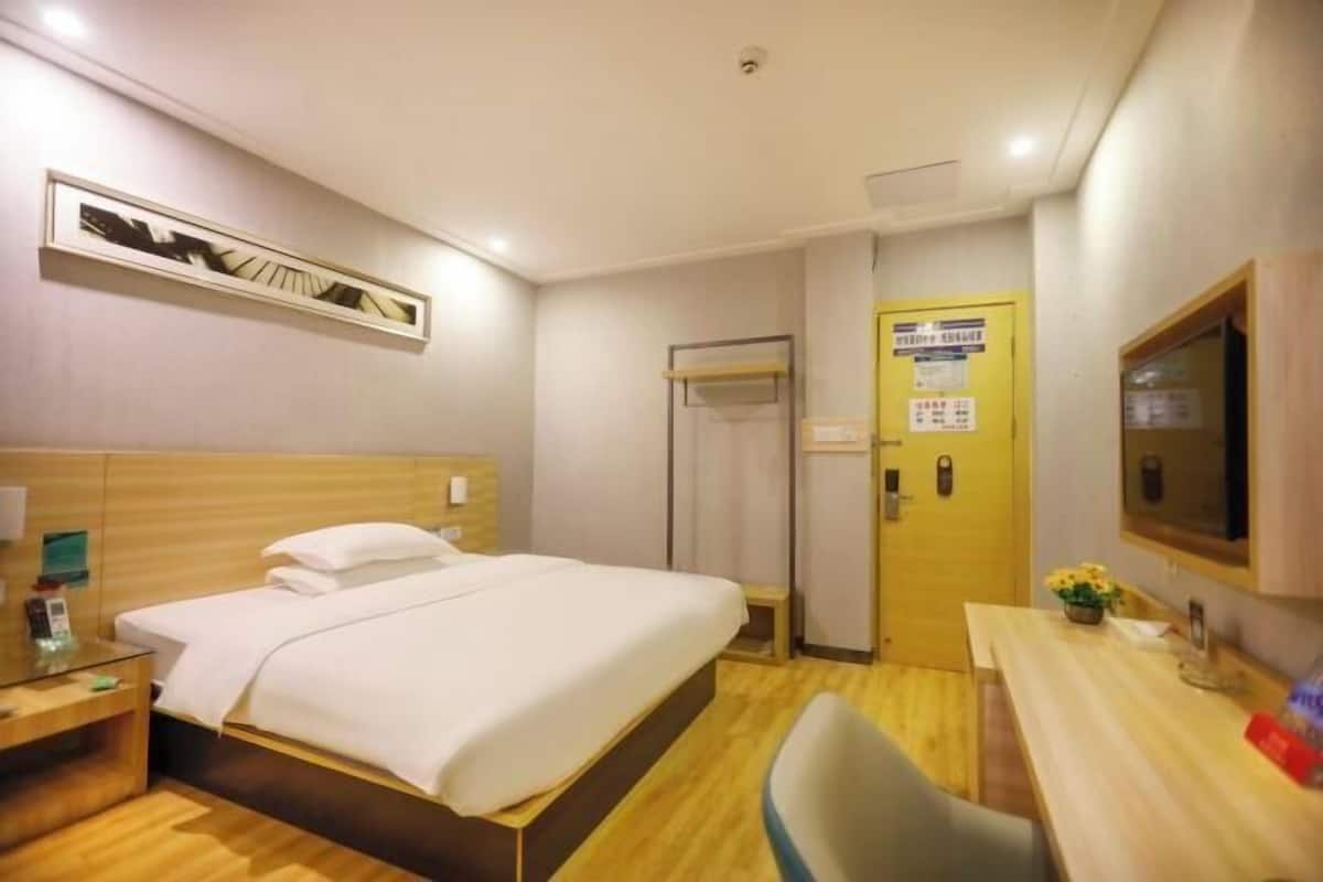 Una habitación de hotel con cama, mesita de noche, silla, escritorio y televisor.