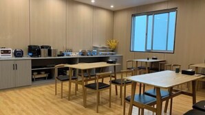 A modern kitchen with built-in appliances and a dining area with wooden tables and chairs. - City Express Hotel (Longzhou)