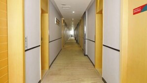 A long, narrow hotel corridor with doors on both sides, a tiled floor, and a ceiling with recessed lighting. - City Express Hotel (Longzhou)